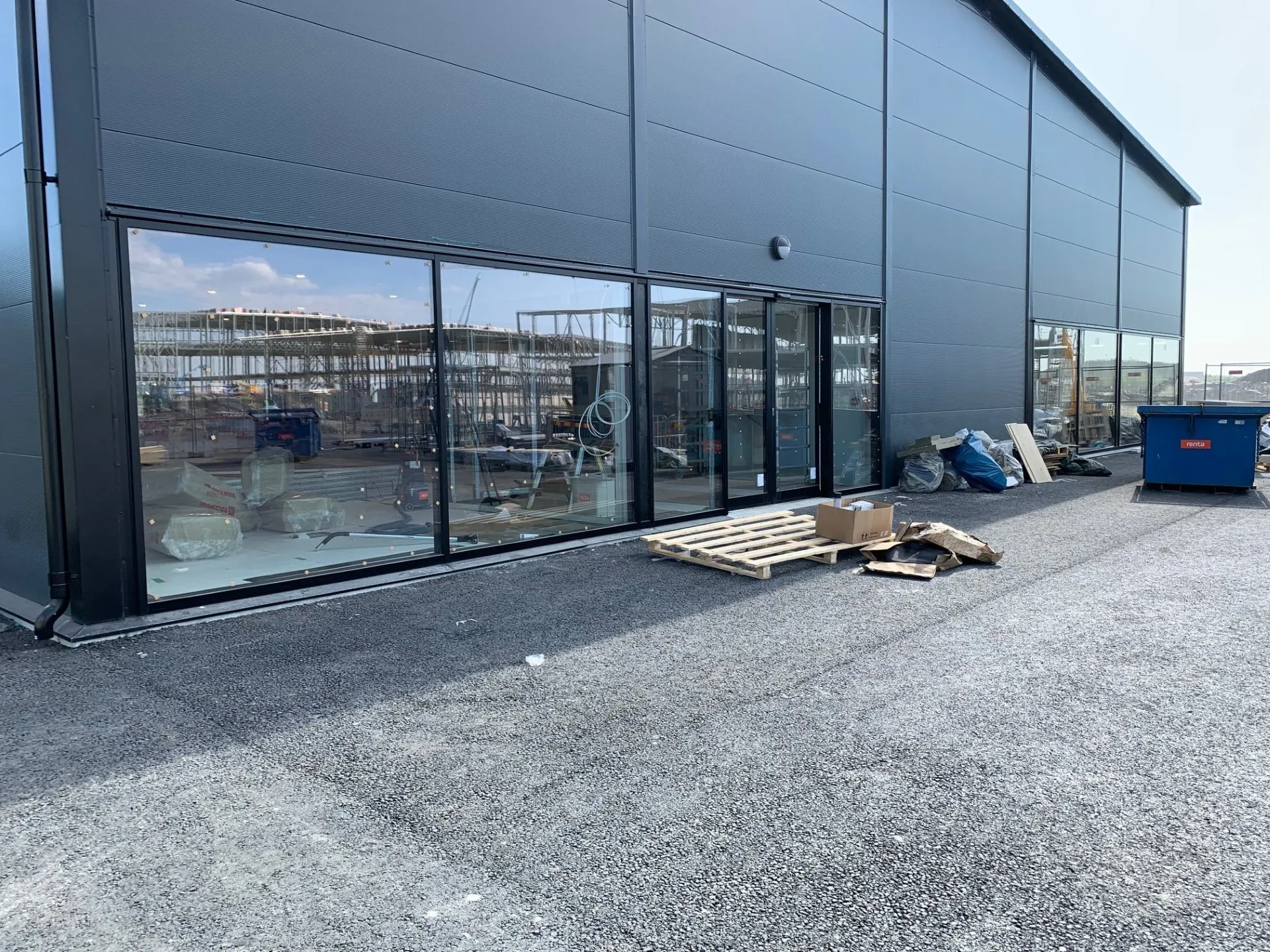 Aluminiumpartier, ny handelsbyggnad – Fasta partier, dörrar och skyltfönster i svartlackerad aluminium. Levererat och monterat parallellt med pågående byggnation.