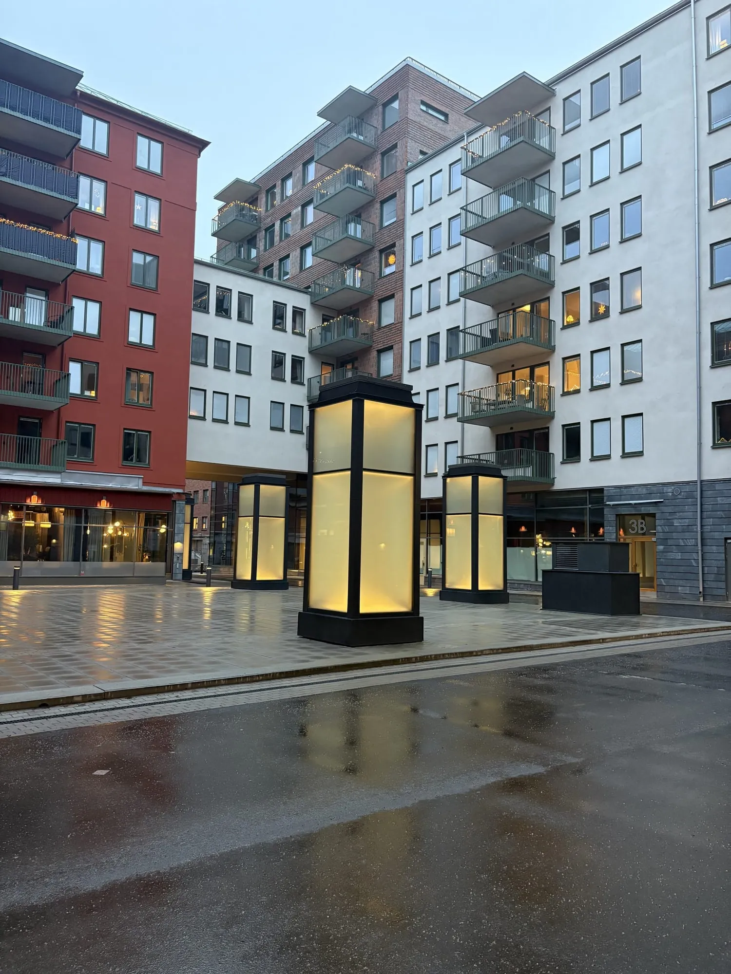 Kv. Fåfängan – Ca 1 200 m² glas- och aluminiumsystem från Schüco, inklusive de belysta glaspelarna på torget. Utförd 2024–2025 som ABT06 åt Görtz Fastigheter — vår enskilt största entreprenad.